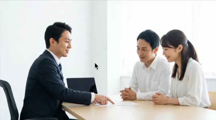 法律事務所で弁護士に借金問題の無料相談をしている日本人の夫婦の様子。専門家のアドバイスを受けて安心している雰囲気が伝わる。